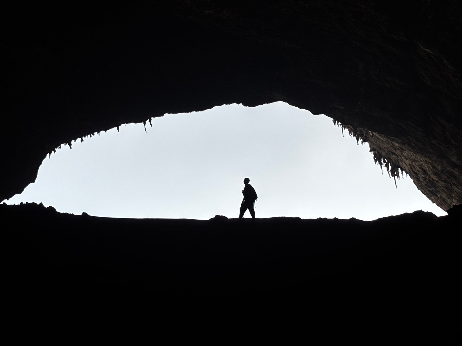 Walker silhouetted in the mouth of Hoq Cave